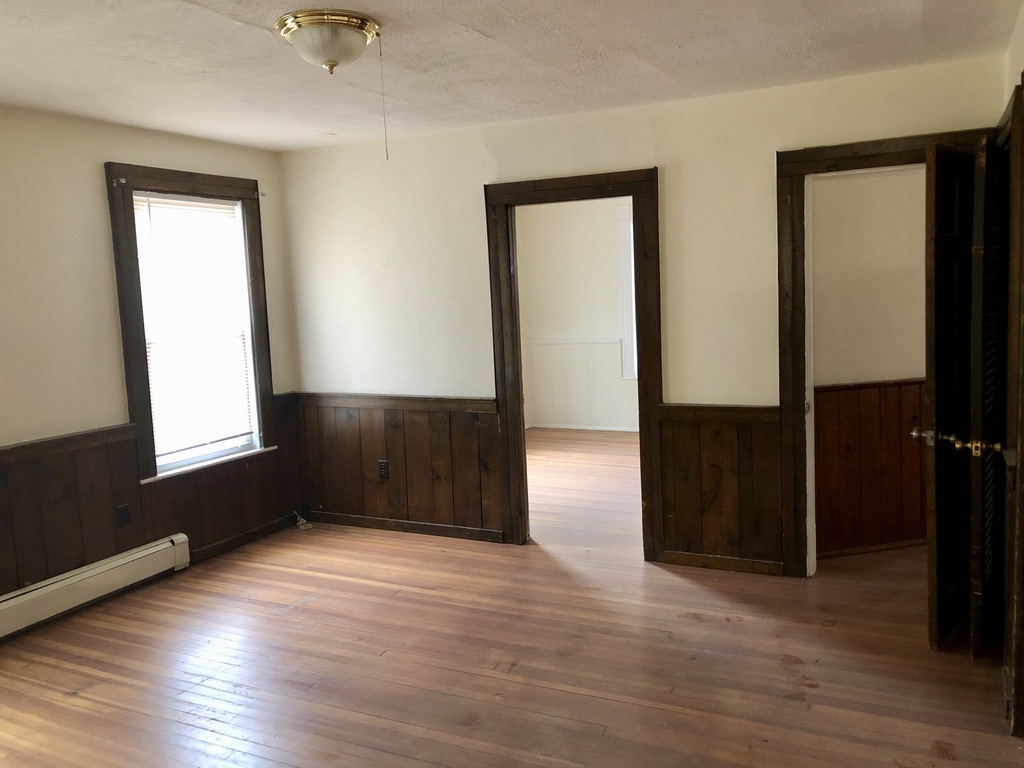 Finished room with preserved dark wood wainscoting and refinished hardwood floors at 36 Pratt Street