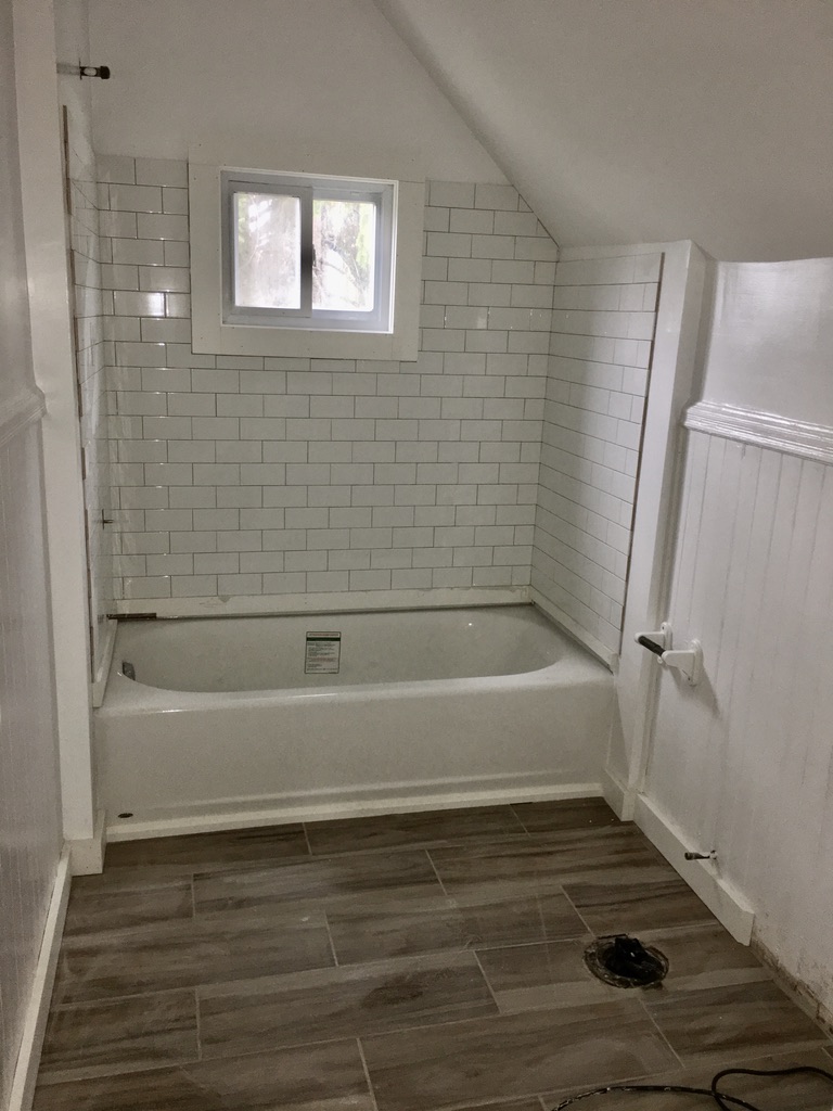 Renovated bathroom with white subway tile, new tub, and wood-look plank flooring at 31 Wallace Street