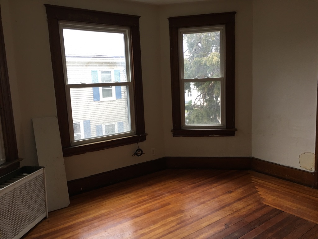 Empty room with peeling paint and old trim at 31 Wallace Street before renovation