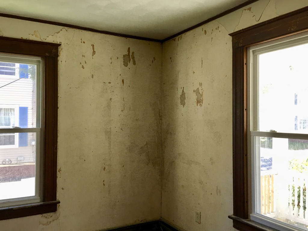 Room corner with damaged plaster walls before renovation at 31 Wallace Street